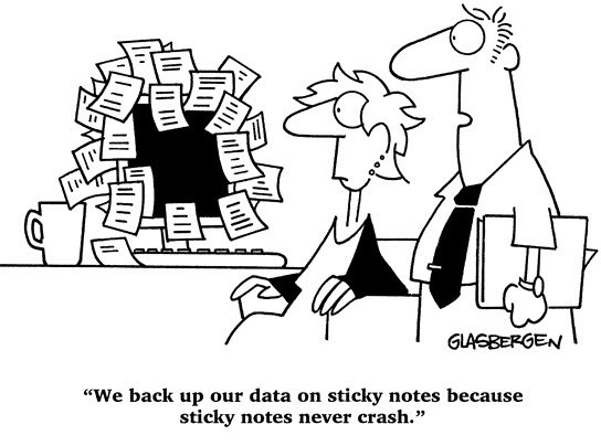 A woman sits at a monitor completely covered with sticky notes with a man standing next to her.