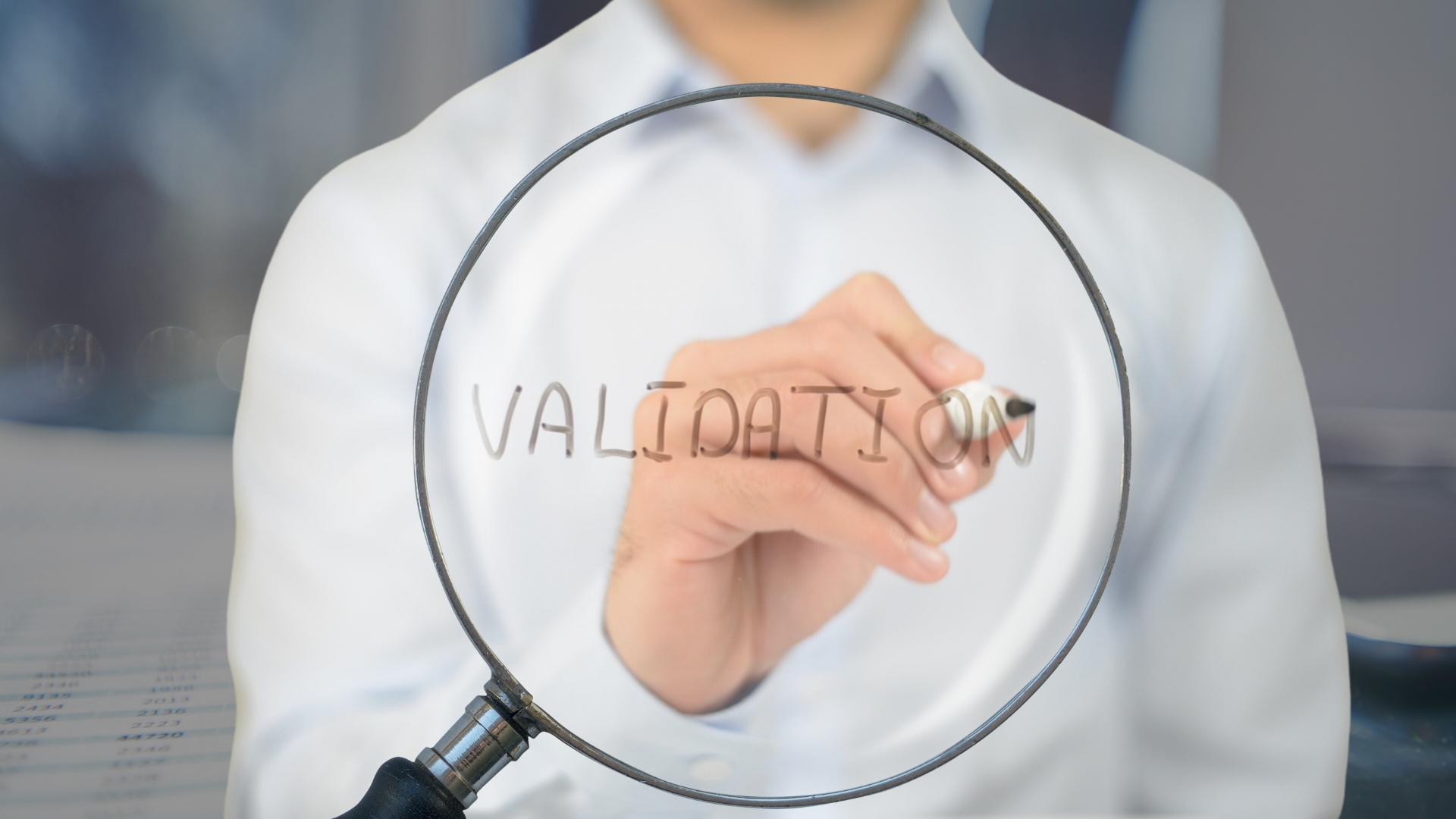 Woman writing the word "validation" on a magnifying glass