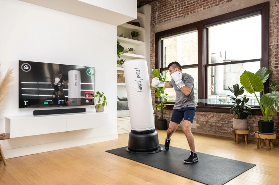 Young man learning to box at home with the help of FightCamp fitness application