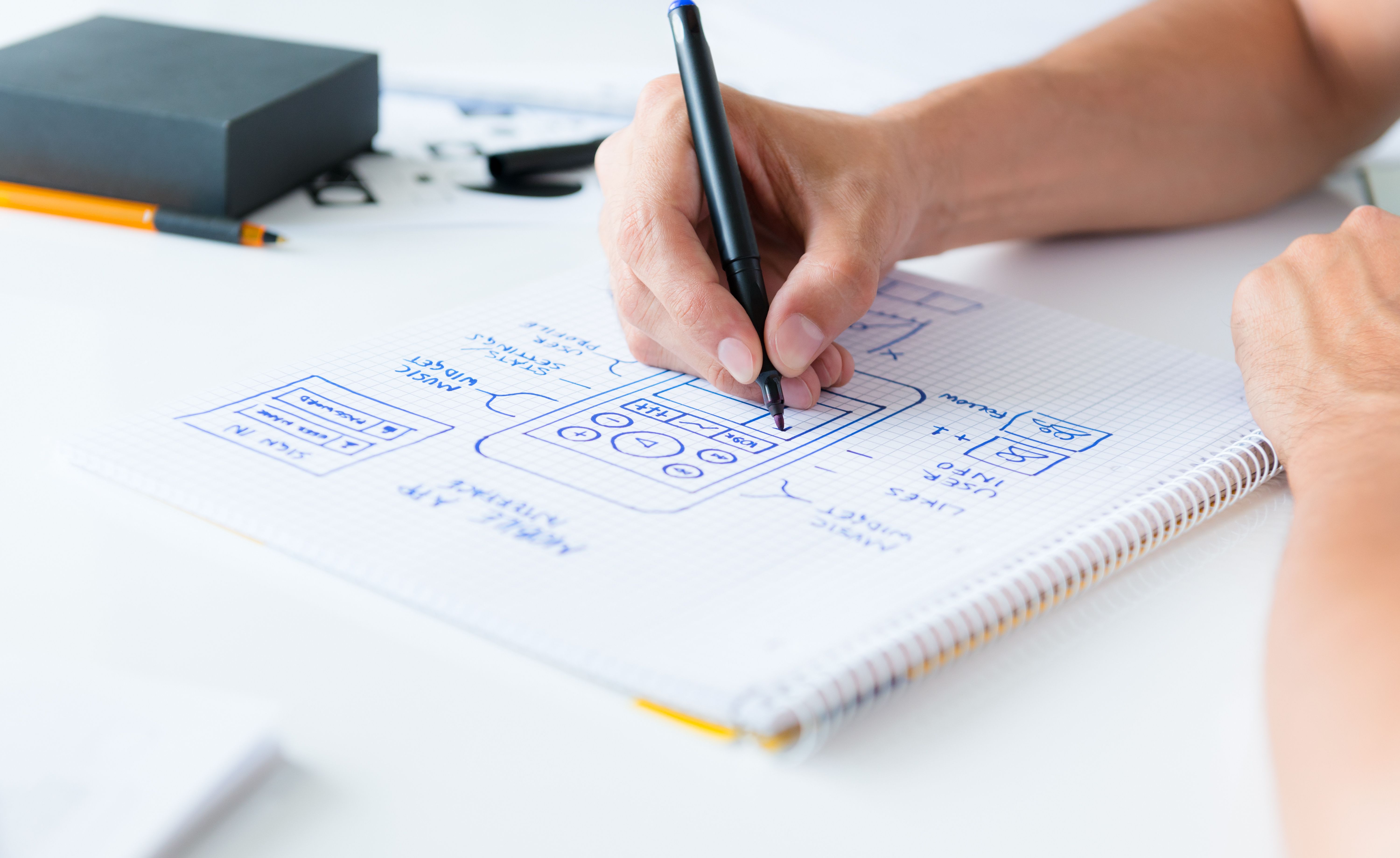 Designer's hand drawing mobile app design in notepad