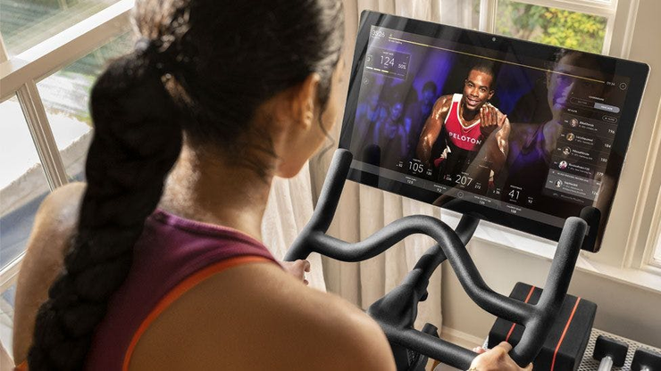 Girl riding a Peloton bike and watching an online fitness class while training